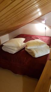 列维Ojuspirtti 26B Levi的一张带三个枕头的床和一张红色的床