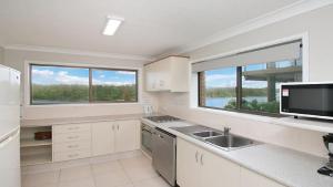 金斯克里福Kingscliff Waters Apartment 5的厨房配有白色橱柜、水槽和2扇窗户。