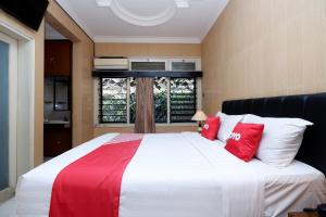 普禾加多OYO 1843 Cahya Nirwana的一间卧室配有一张带红色和白色枕头的大床