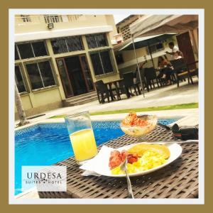 瓜亚基尔乌尔德萨套房酒店的一张桌子,上面放着一盘食物和一杯橙汁