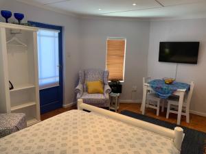 克莱因蒙德Bungalow by the sea near Cape Town的一间卧室配有一张床、一把椅子和一张桌子