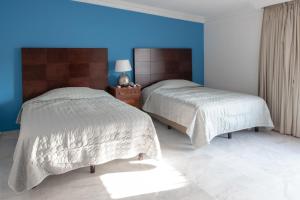 马萨特兰Loft Sabalo - Pet Friendly的卧室设有两张床铺,拥有蓝色的墙壁
