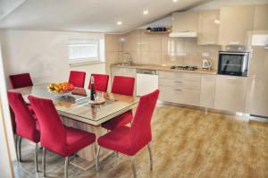 斯普利特Apartman Đoni的厨房配有木桌和红色椅子