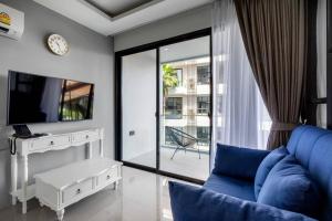 苏林海滩PALMYRAH SURIN, MODERN 1BR with Terrace, 150 meters to Surin Beach的客厅配有蓝色的沙发和电视