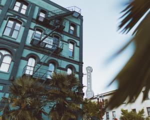 波特兰The Society Hotel的一座蓝色的建筑,前面有棕榈树