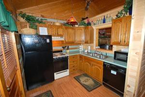 鸽子谷Mountain Memories的厨房配有木制橱柜和黑色冰箱。