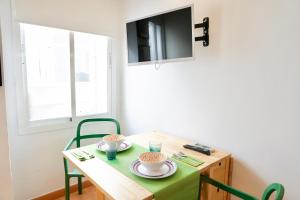 马拉加Alemania & SOHO by ELE Apartments的一张带绿色椅子的小桌子和一台电视