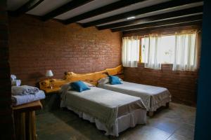 特来凡林Hostería La Portada的一间卧室设有两张床和砖墙