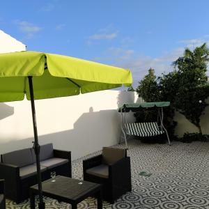 蓬塔德尔加达Helena's House的一个带绿色遮阳伞和桌椅的庭院
