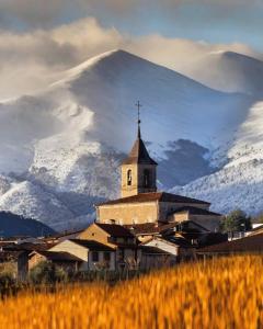 BerceoCasa Rural Nestazar II的一座教堂,其背景是一座白雪覆盖的山