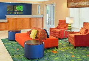 费耶特维尔Country Inn & Suites by Radisson, Fayetteville I-95, NC的客厅配有橙色沙发和两把椅子