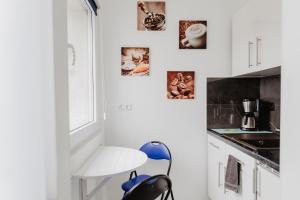 盖尔森基兴SK Apartments - Blue的白色的厨房,配有蓝色椅子和墙上的照片