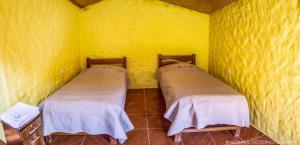 卡瓦纳科德Paraiso Las Palmeras Lodge的黄色墙壁客房的两张床