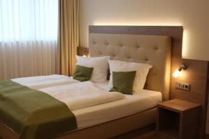 帕德博恩兰德豪斯贾格尔克鲁格酒店的一间卧室配有一张带绿色和白色枕头的大床