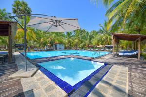 卡尔皮蒂耶De Silva Palm Resort的一个带遮阳伞和棕榈树的游泳池
