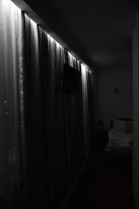 MăgureleHotel Magurele的黑暗的客房设有窗户、窗帘和电视。