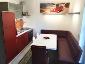 汉堡Ferienhaus Feel like Home Barbecue的一间小厨房,配有一张白色的桌子和红色的橱柜