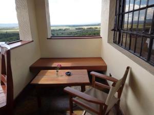 奈瓦沙Mwanzo Lodge的窗户客房内的小桌子和两把椅子