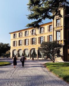 Cazzago San MartinoVilla Biondelli Wine & Suites的两个人在建筑物前的路上走