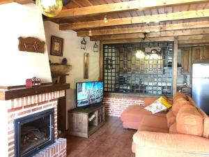 NavalguijoCasa Rural El Castaño的带沙发和壁炉的客厅