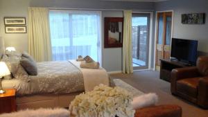 拉塞尔Pukeko Nest的一间卧室配有一张床、一台电视和一张沙发