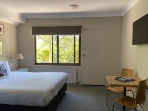 金德拜恩金迪酒店的一间卧室配有一张床、一张书桌和一个窗户。
