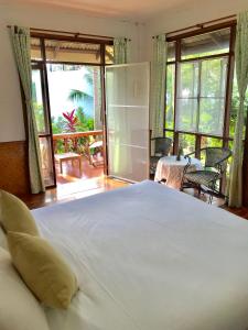 湄南海滩Mali House的一间带一张白色大床的卧室和一个阳台