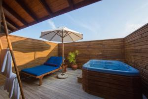 丹格迪维拉蔓豪岛度假酒店的甲板上设有热水浴池、椅子和遮阳伞