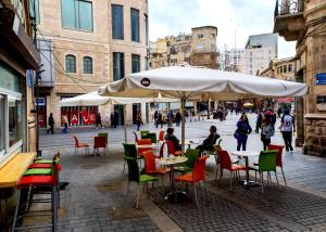 耶路撒冷The boutique的室外咖啡厅配有桌椅和遮阳伞