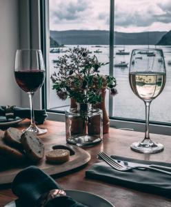 波特里The Rosedale Hotel & Restaurant的桌子上放两杯葡萄酒,享有水景