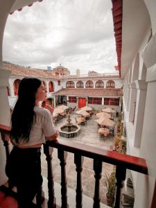 阿亚库乔Hotel Santa Rosa的站在阳台的女人,眺望着庭院