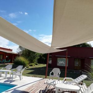 诺诺La Celina Casas de Campo的一组椅子和一个带白色遮阳伞的庭院