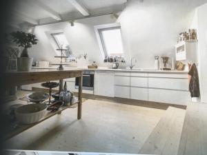 埃贝尔托夫特Ebeltoft的厨房配有白色橱柜和木制台面