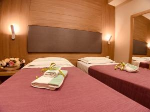 夸利亚诺斯密拉尔多酒店的两张位于酒店客房的床,配有毛巾