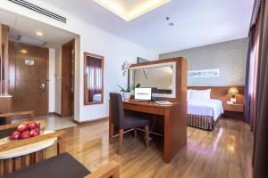 胡志明市Saigon Hotel的酒店客房配有一张桌子、一张床和镜子