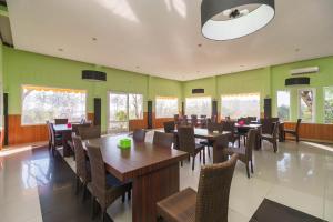 明古鲁省RedDoorz Syariah At Hotel Putri Gading Bengkulu的餐厅设有木桌和椅子,拥有绿色的墙壁