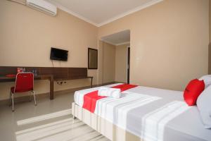 明古鲁省RedDoorz Syariah At Hotel Putri Gading Bengkulu的一间卧室配有一张床、一张书桌和一台电视