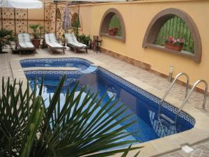 希典海特酒店的一座游泳池,位于一座带椅子的庭院内,毗邻一座建筑