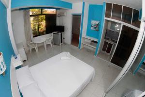 博卡奇卡Aparta Hotel Azzurra的卧室配有白色的床和桌椅