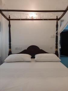 米瑞莎Hill House Rest的一张带两个白色枕头的床和木制床架