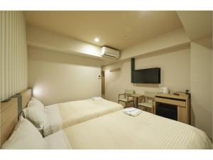 镰仓市Sotetsu Fresa Inn Kamakura-Ofuna Higashiguchi的酒店客房设有两张床和电视。
