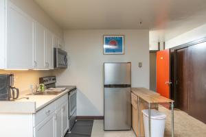 哥德伍德East Condo #208的厨房配有不锈钢冰箱和桌子