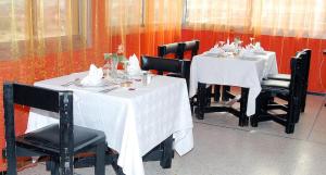 海尼夫拉HOTEL CONTINENTAL Khénifra的用餐室配有白色桌子和黑色椅子