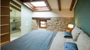 Garínoain拉克阿克乡村民宿的一间卧室设有一张带石墙的大床