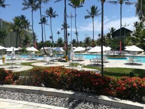 嘎林海斯港Marulhos Resort Porto De Galinhas的一个带桌椅的度假村游泳池,并种植了棕榈树