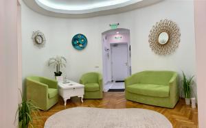 布加勒斯特Victoria Luxury Apartment 11的一间设有两张绿色椅子和一张桌子的等候室