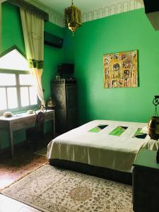 瓦尔扎扎特Le Petit Riad Maison d'hôtes的一间卧室设有绿色的墙壁、一张床和一张桌子