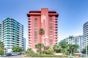迈阿密海滩Inviting condo with pool & beach access的一座高大的红色建筑,有棕榈树和建筑
