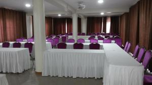 MityanaMakanHill Resort Hotel的一间会议室,配有白色的桌子和紫色的椅子