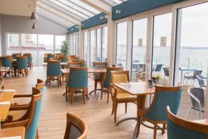 科芙水滨酒店的餐厅设有桌椅和窗户。